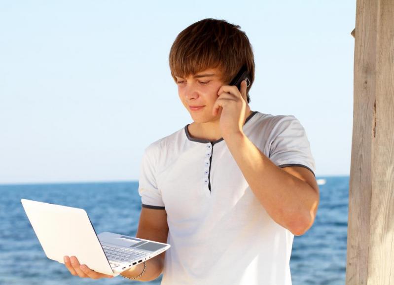 teenage-boy-in-white-shirt-on-phone-looking-at-computer